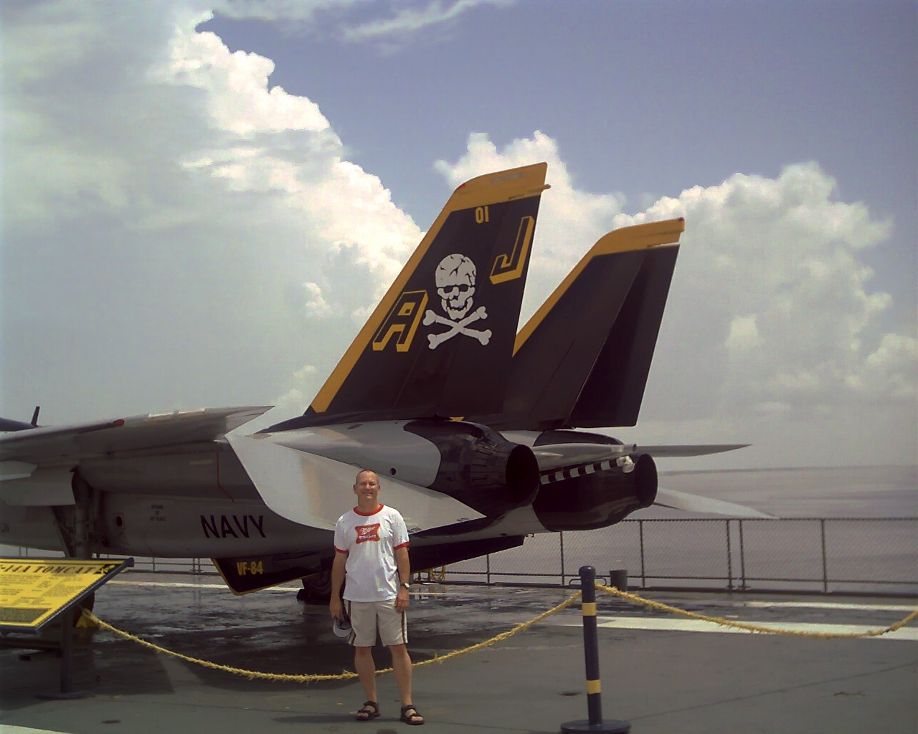 Mike Kimbro in front of the tail of an F-14A Tomcat on the flight deck of the USS Lexington